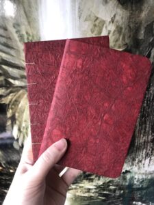 Deux carnets avec une couverture en papier cristal rouge, réalisés à la main par un Esprit dans la Lune.
